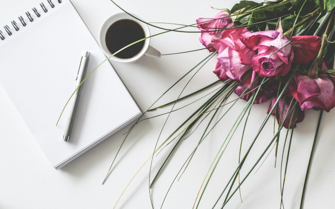 note pad next to coffee and roses